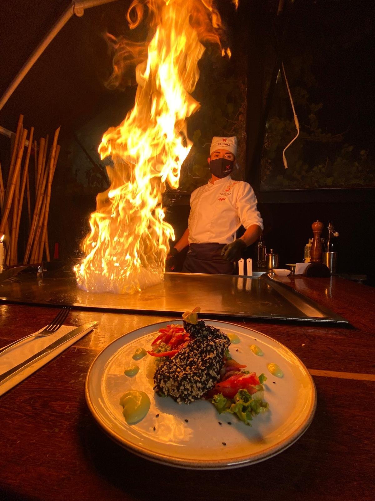 A plated dish in front of teppanyaki flames