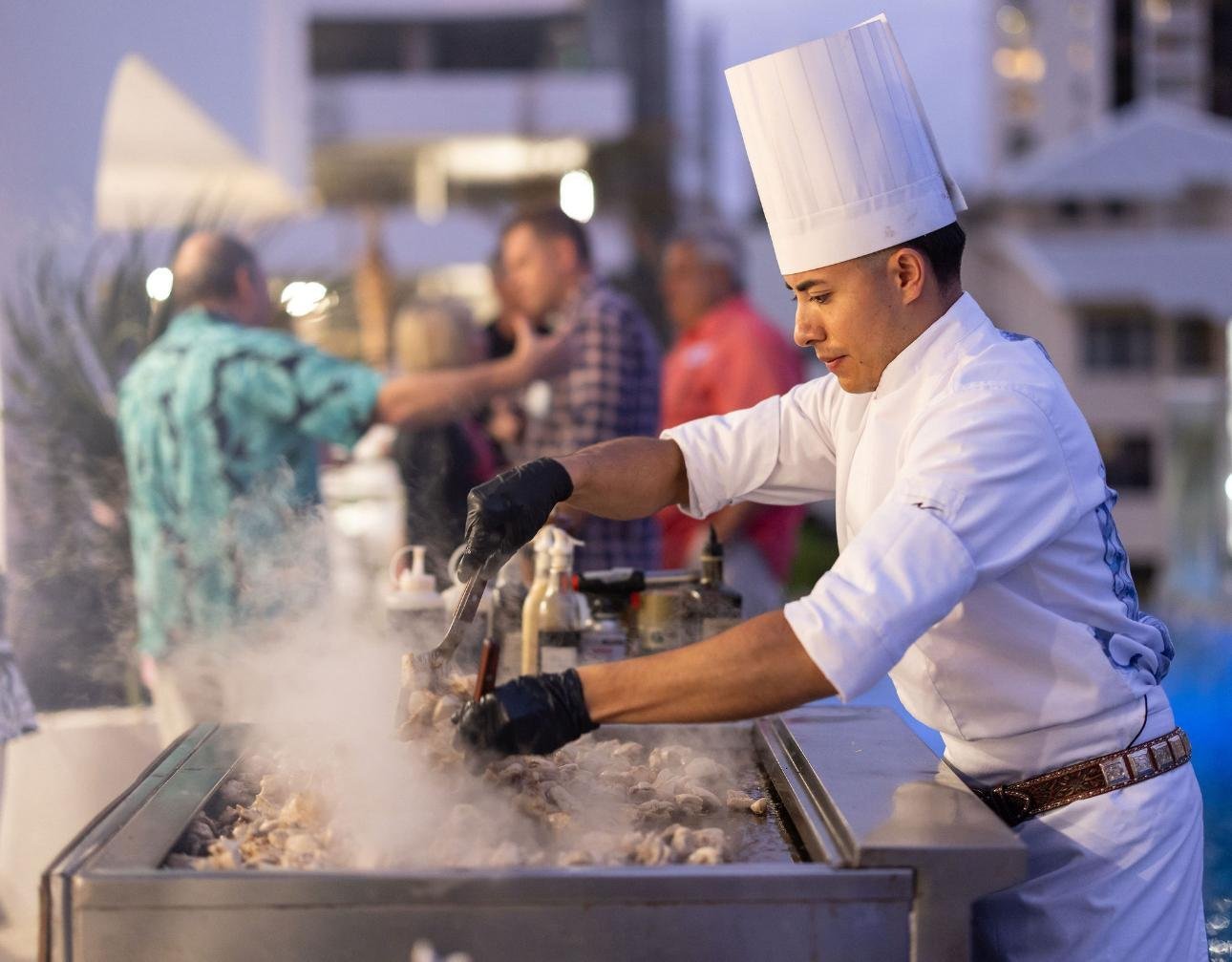 Chef Miguel working the plancha grill amid the smoke